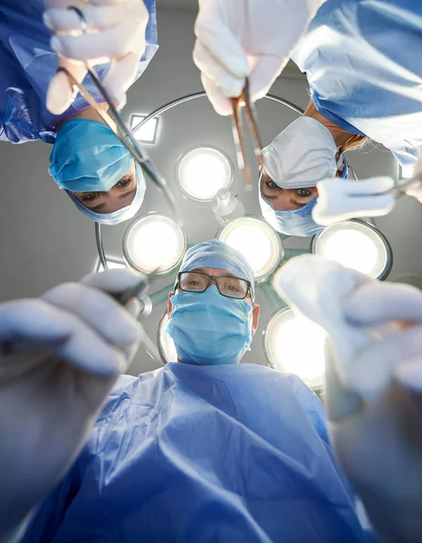 手術中に患者を見ている間 はさみ タンポンを持つ医師の下からの眺め 手術室で整形手術を行うチーム 薬の概念 — ストック写真