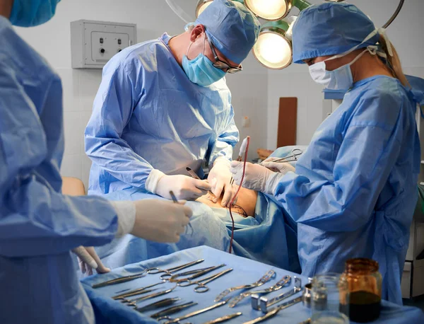 장갑과 마스크를 수술실에서 성형수술을 있습니다 수술대 옆에서 기구를 보조로 의사들이 — 스톡 사진