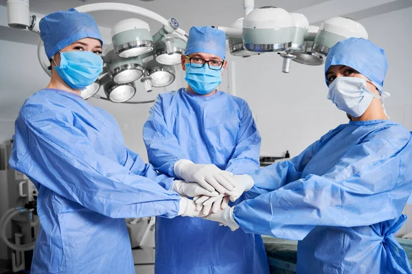 医療従事者は団結の象徴として手を携えている 白い滅菌手袋 青い外科的制服を着て手のスタックを持つ医師のグループ チームワーク 医学の概念 — ストック写真