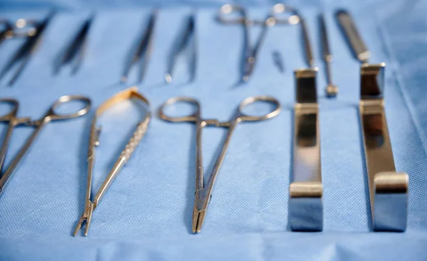 各种用于蓝色医用布整形手术的不锈钢工具 手术室的剪刀 钳和牵引机 美容外科和医疗器械的概念 — 图库照片