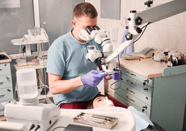 Άντρας Οδοντίατρος Που Χρησιμοποιεί Οδοντιατρικό Μικροσκόπιο Ενώ Ελέγχει Γυναικεία Δόντια — Φωτογραφία Αρχείου