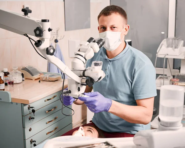Αρσενικό Στοματολόγο Αποστειρωμένα Γάντια Χρησιμοποιώντας Οδοντιατρικό Διαγνωστικό Μικροσκόπιο Ενώ Γυναίκα — Φωτογραφία Αρχείου