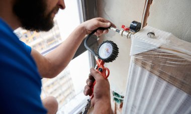 Tesisatçı boruları yeni tesisattaki sızıntıları kontrol etmek için basınçlı havayla dolduruyor, ısıtma sisteminin gaz sıkılığını kontrol ederken hava kompresörü kullanıyor. Ev yenileme kavramı