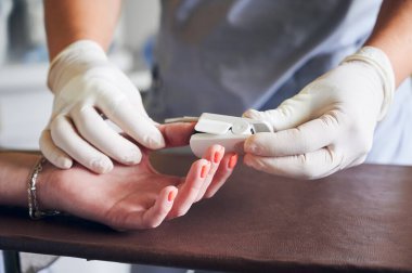 Tıbbi işçilerin ellerini kapatın ve ameliyattan önce nabız oksimetresi sensörünü kadın parmağına takın. Doktor hastanın eline oksijen doygunluğunu ve nabız oranını izlemek için klipsli cihaz takıyor..