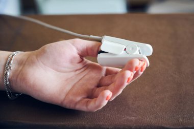 Oksijen doygunluğunu ve nabzını ölçmek için kadın eli klipsli cihazla kapatın. Baş parmağında nabız oksimetresi olan bir kadın hasta. Tıp, sağlık ve nabız oksimetrisi kavramı.