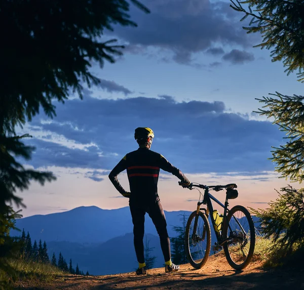 后视镜 骑自行车的人站在那里 骑着自行车 看着美丽的风景 山峰和日落 周围环绕着云杉 正方形图片 积极生活方式概念 — 图库照片