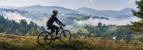 Homem Andando Bicicleta Colina Gramada Olhando Para Belas Montanhas Enevoadas — Fotografia de Stock