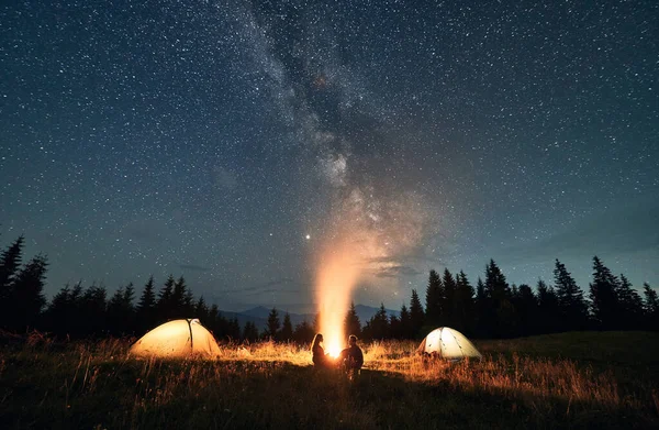 야영지 텐트와 캠프파이어 등산객들이 별빛으로 반짝이고 여행자들이 마법의 모닥불 근처에 — 스톡 사진