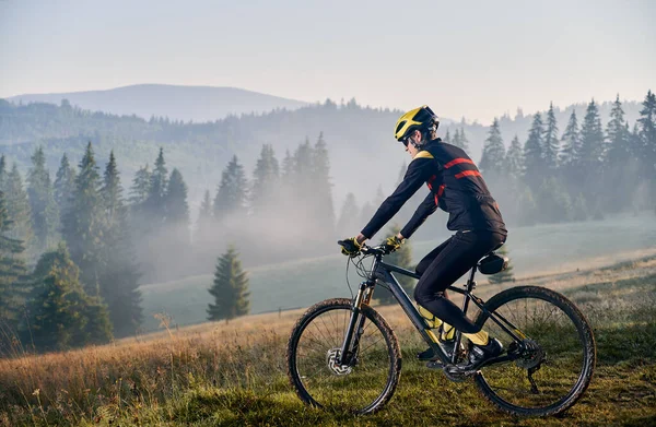 在雾蒙蒙的清晨 男人骑自行车在山上的水平快照 在美丽的风景下骑自行车下山的侧视图 自行车和自然的概念 — 图库照片