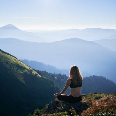 Esmer kadının sabah Lotus pozunda yoga çalışmasını. Meditasyon yapan dişi dağlarda dinleniyor. Formda vücut kavramı.