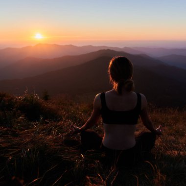 Özel spor giyim giymiş genç bir kadının temiz hava üzerine meditasyon yapışının arkası. Doğayla özgürlük kavramı.