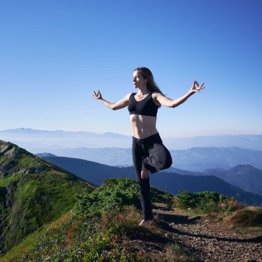 Spor kıyafetli, tek ayak üzerinde dengede duran ve dışarıda yoga yaparken Gyan Mudra el hareketi yapan sağlıklı bir kadın. Dağlarda yoga yapan atletik genç bir kadın..