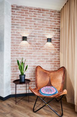 Büyük ahşap sandalyeli çatı katında dinlenme yeri manzarası. İki abajurlu tuğla duvarlı, modern daireye ait. Rahat tasarım kavramı.