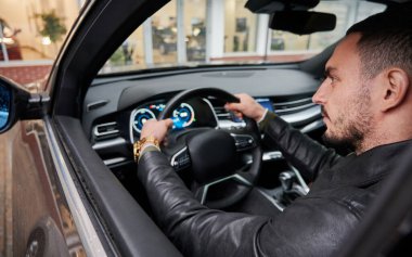 Yakışıklı genç adam yeni arabayı test ediyor, bir arabanın içinde oturuyor..