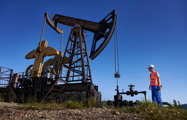 与无云天空操作员站在石油管道附近与扳手和准备维修石油钻井 钻井泵钻机工作服中的油工监测适用性 — 图库照片
