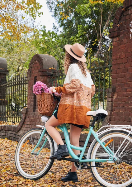 베이지 모자를 곱슬머리의 매력적 바구니에 분홍색 유행하는 가디건 자전거를 매력적 — 스톡 사진