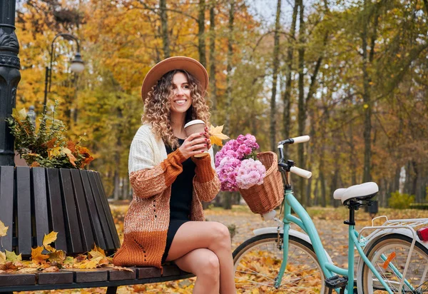 가을에 자전거타고 공원에서 커피마시면서 숙녀가 풍경을 감상하며 자전거를 야외에서 벤치에 — 스톡 사진