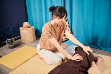 Masör Tayland yogası masajı yapıyor. Kadın terapist, kadın hasta için evde geleneksel masaj tedavisi uyguluyor. Müşteri paspasın üzerinde uzanıyor, meditasyon yapıyor, sakin bir atmosferde el masajının keyfini çıkarıyor..