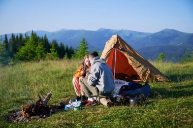 Sabahları iki çadırı olan manzaralı dağ kampı. İki kampçı, bulutsuz gökyüzünün altında yuvarlanan dağların huzurlu manzarasının keyfini çıkarıyorlar. Resimli gündoğumu manzarası, huzurlu ve rahat bir açık hava deneyimi yaratıyor..