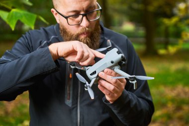 Düşen yapraklarla dolu sakin bir parkta, gözlüklü bir adam İHA 'sını dikkatlice ayarlar, bir uçuş için hazırlanır. Onu çevreleyen canlı doğa..