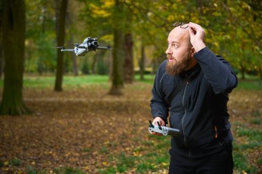 Bir adam canlı bir parkta duruyor. Yakınlarda bir dron uçarken şaşırıyor. Sahne, sonbaharın güzelliğini renkli yapraklar ve huzurlu bir atmosferle yakalıyor..