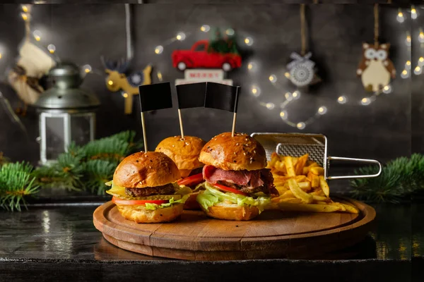 Tahtada ev yapımı hamburgerler ve patates kızartması duvarda Noel süsü, yakın çekim manzarası.