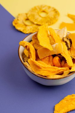 Sarı ve mor arka planda çeşitli vejetaryen etleriyle seramik kase, üst manzara. Portre yönelimi