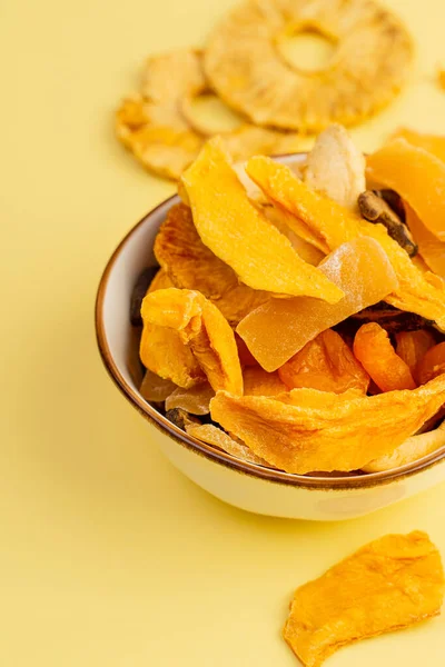 Sarı arka planda çeşitli vejetaryen pastırmalı seramik kase, üst manzara. Portre yönelimi