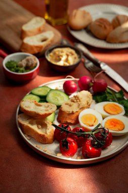 Terracotta arka planında Akdeniz usulü kahvaltı tabağı. Portre orinetasyonu, yakın plan görünümü