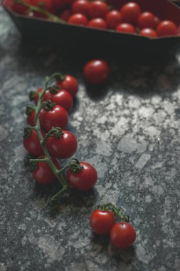 Granit arka plandaki dallarda kiraz domatesleri, yakın çekim manzarası. Portre yönelimi