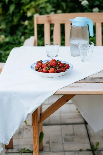 Fresas frescas en un plato en una mesa de jardín que se sirve para el desayuno —  Fotos de Stock