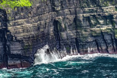 Moher Claire County İrlanda 'nın Renkli Cove Waves Deniz Kuşları Yuvaları Tepeleri. Uçurumlar Atlantik Okyanusu 'nun 270 metre yukarısına yükseliyor ve İrlanda kıyısı boyunca 9 mil boyunca koşuyor. Unesco sitesi İrlanda 'da en çok ziyaret edilen yerlerden biri ve birçok film sitesi. 
