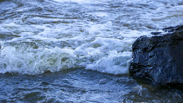 波が海岸に走って岩に衝突し海岸近くに多くの水しぶきや飛沫を生み出します 石の小石の海岸付近の荒天時の川のサーフィン — ストック写真