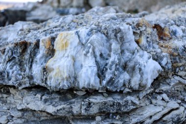 Farklı renkte kuvars kayaları. Gri, beyaz, turuncu kuvars depozitoları. Çeşitli taş birikintilerinde ve farklı kaya katmanlarında kalipdonik çeşitlilikte işlenmemiş yarı değerli taşlar..