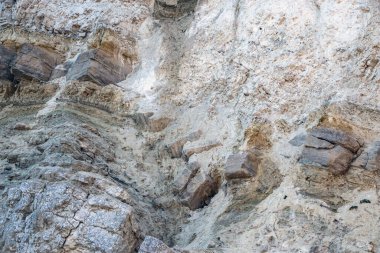 Alçıtaşı çıkarmak için bir taş ocağında kumlu alçıtaşı kesimi. Kum, kil, alçı taşı, kuvars ve alçı taşı içeren farklı toprak katmanlarının dağ dokuları erozyondan sonra.