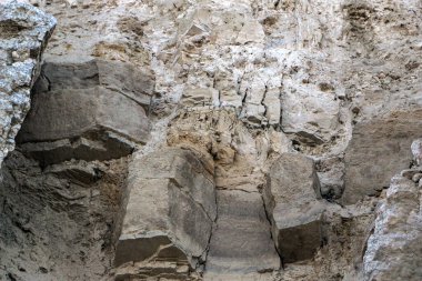 Alçıtaşı çıkarmak için bir taş ocağında kumlu alçıtaşı kesimi. Kum, kil, alçı taşı, kuvars ve alçı taşı içeren farklı toprak katmanlarının dağ dokuları erozyondan sonra.