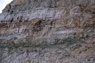 Alçıtaşı çıkarmak için bir taş ocağında kumlu alçıtaşı kesimi. Kum, kil, alçı taşı, kuvars ve alçı taşı içeren farklı toprak katmanlarının dağ dokuları erozyondan sonra.