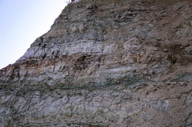 Alçıtaşı çıkarmak için bir taş ocağında kumlu alçıtaşı kesimi. Kum, kil, alçı taşı, kuvars ve alçı taşı içeren farklı toprak katmanlarının dağ dokuları erozyondan sonra.