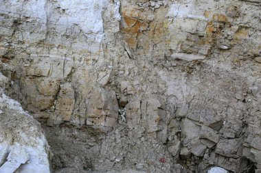 Alçıtaşı çıkarmak için bir taş ocağında kumlu alçıtaşı kesimi. Kum, kil, alçı taşı, kuvars ve alçı taşı içeren farklı toprak katmanlarının dağ dokuları erozyondan sonra.