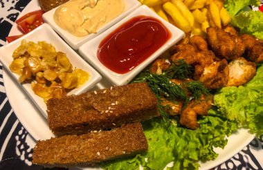 Bira tabağı ve çeşitli bira çeşitleri sarımsaklı ekmek, kızarmış ekmek, kızarmış ekmek, kanat, küçük turşu mantar, patates kızartması, otlar ve küçük vazo soslar..