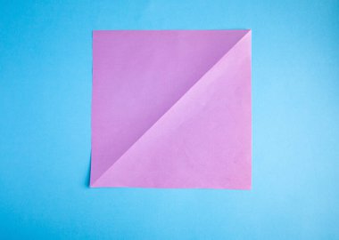 Mavi arkaplandaki renkli kağıttan bir origami tavşanı yaratmak için adım adım talimatlar, dekoratif bir Paskalya partisi süsü ya da küçük Paskalya hediyeleri için.