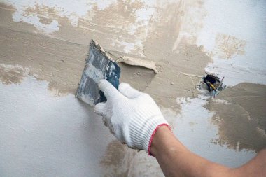 Erkekler spatula ve macunla birlikte kumaş eldiveni veriyorlar, mastiği duvara, tavanı da yüzeye uyguluyorlar. Odanın iç tasarımı için bir spatula ile mastik uygulanması süreci. 