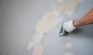 Erkekler spatula ve macunla birlikte kumaş eldiveni veriyorlar, mastiği duvara, tavanı da yüzeye uyguluyorlar. Odanın iç tasarımı için bir spatula ile mastik uygulanması süreci. 