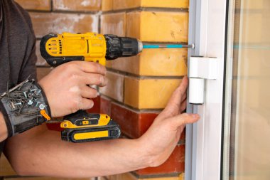 Bir inşaat işçisinin erkek elleri vidaları sıkılaştırır ve tamir eder ve kablosuz bir tornavidayla ev dekorasyonu ve iç dekorasyon için kendi kendine dokunur.. 