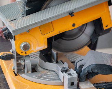 Tahta bir tahtadan elektrikli elektrikli testere testeresi kesen bir inşaat işçisinin erkek elleri. Tahta kesme işlemi neşter dönüşü ve tozlu bulut elektrikli testere ile yapılıyor.
