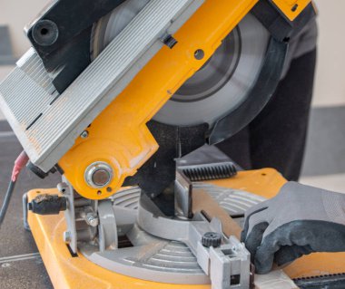 Tahta bir tahtadan elektrikli elektrikli testere testeresi kesen bir inşaat işçisinin erkek elleri. Tahta kesme işlemi neşter dönüşü ve tozlu bulut elektrikli testere ile yapılıyor.