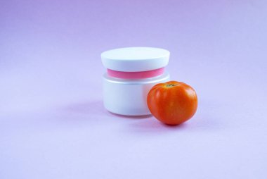 Beyaz bir kavanozda cilt bakımı için krem ve maske ve parlak sulu domateslerin yanında bir şeker kutusuyla tüp. Vitaminli ve antioksidanlı domatesli faydalı doğal kozmetik ürünleri kavramı.