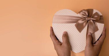 Aşk ve Sevgililer Günü Konsepti. Altın Kalp Şekil Hediye Kutusu 'nu tutan eller. Üst Görünüm