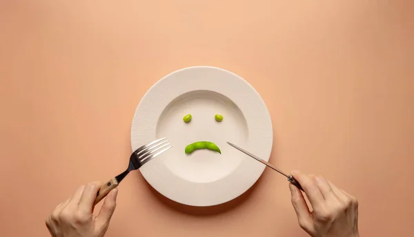 卫生保健概念中的饮食或厌食症 吃的混乱 体重减轻 年轻妇女用叉子和刀叉吃盘子里的青豆 不快乐的食物顶视图 — 图库照片
