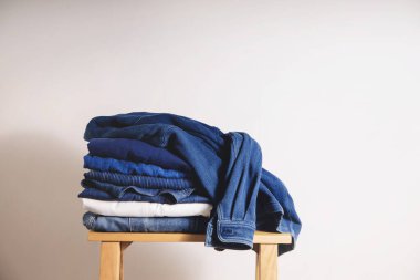 Kıyafet Konsepti. Whaite Duvarı 'nın yanındaki tahta bankta giysi yığını. Mavi Donanma Tonu